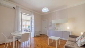 Een moderne woonkamer met een eethoek, een bank, een bijzettafeltje en een keuken met een aanrecht en kastjes.