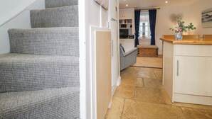 Eine Treppe führt zu einem Wohnbereich mit einer Couch, einer Bank und einem kleinen Tisch mit einer Vase.