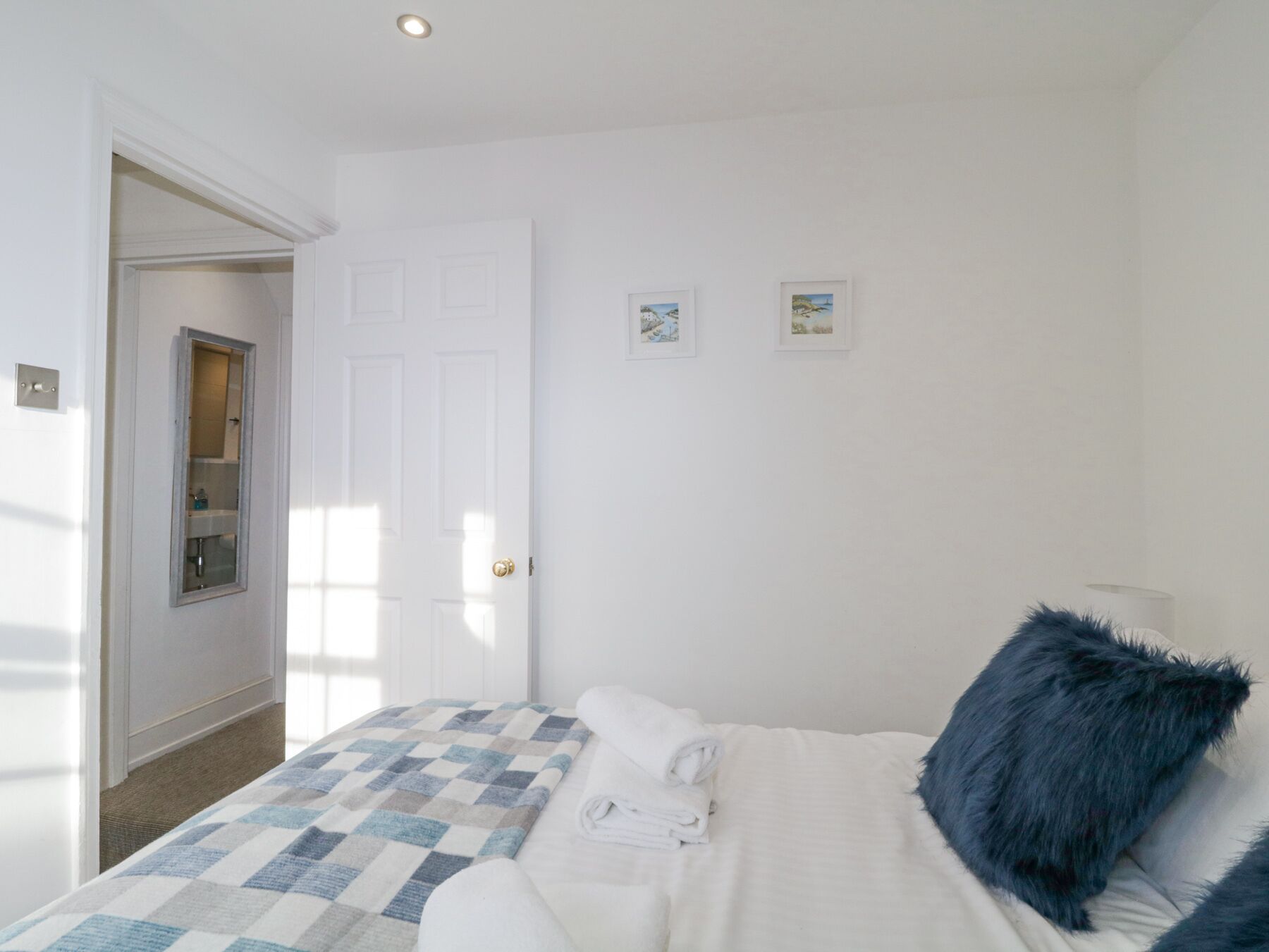 A bedroom with a bed, a window, a door, and a small wall-mounted shelf.