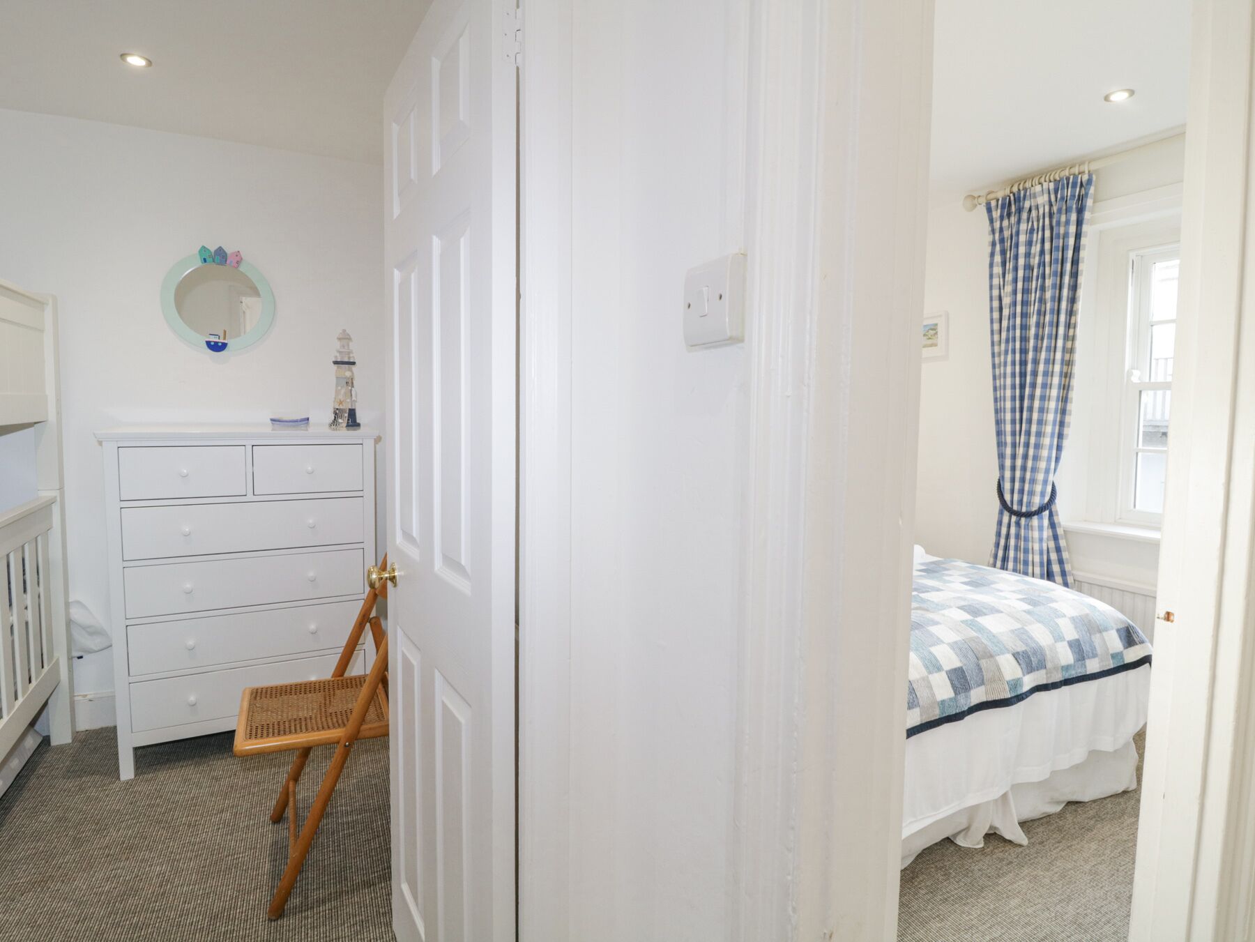 A bedroom with a bed, a dresser, a chair, and a door.