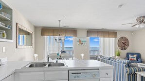 A modern kitchen with a central island, white cabinetry, and a built-in dishwasher.
