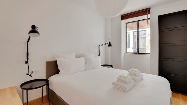 Une chambre d’hôtel moderne, dotée d’un grand lit, de deux tables de chevet, d’un bureau et d’une fenêtre offrant une vue agréable.