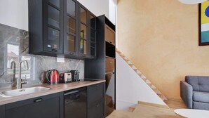 Une cuisine moderne avec des meubles de rangement aux couleurs sombres, un évier en acier inoxydable et un lave-vaisselle encastré.