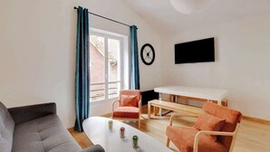 Un salon moderne comprenant un canapé, deux fauteuils, une table basse et un téléviseur fixé au mur.