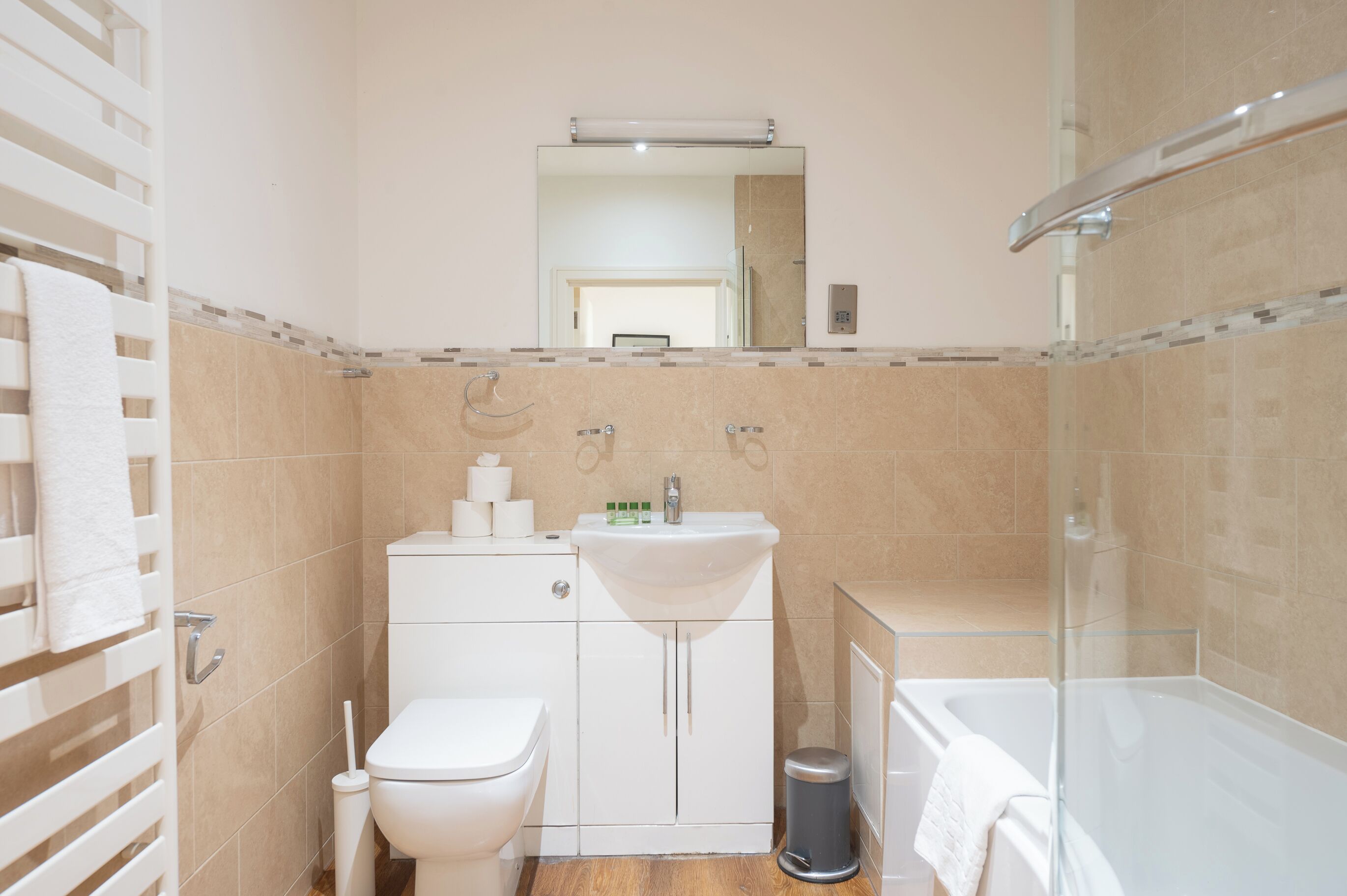 Un baño moderno con inodoro, lavamanos y cabina de ducha de vidrio.