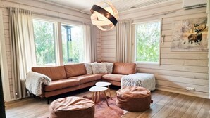 A cozy living room with a brown sectional sofa, two round ottomans, a white coffee table, and a large window with curtains. - Villa Rantatuuli, Himosranta (Keski-Suomi)