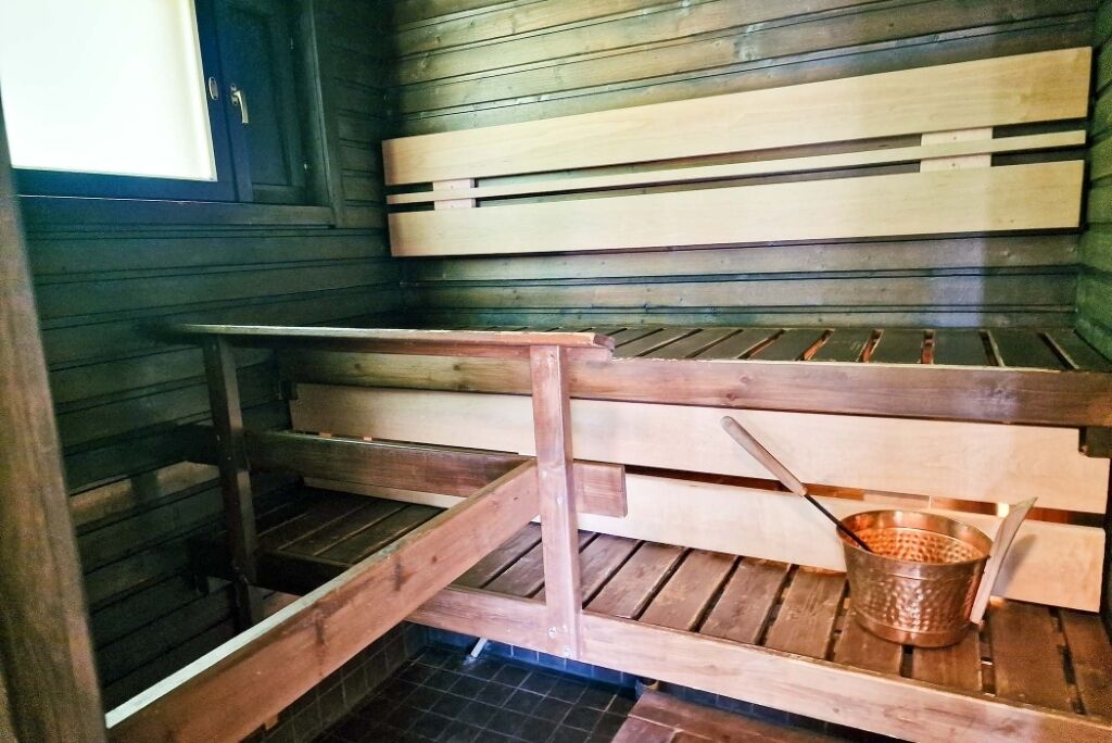 Una sauna con bancos de madera y un cubo de metal.