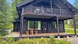 A wooden cabin with a balcony, large windows, and a deck area. - Villa Rantatuuli, Himosranta (Keski-Suomi)