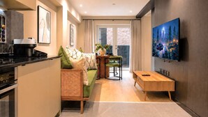 A modern kitchen with a dining area, a sofa, and a TV mounted on the wall.