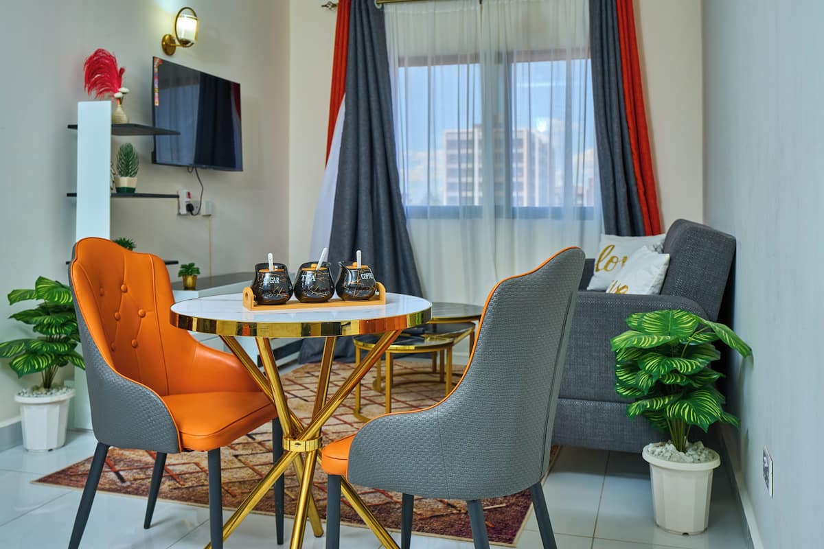 A modern living room with a round table, two chairs, a sofa, and a television.