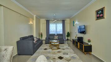 Ein Wohnzimmer mit einer Couch, einem Couchtisch, einem Fernseher und einer Pflanze.