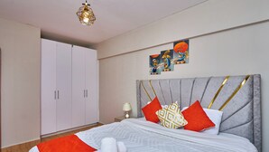 Une chambre à coucher comprenant un lit, une armoire, une table de chevet et une œuvre d’art murale.