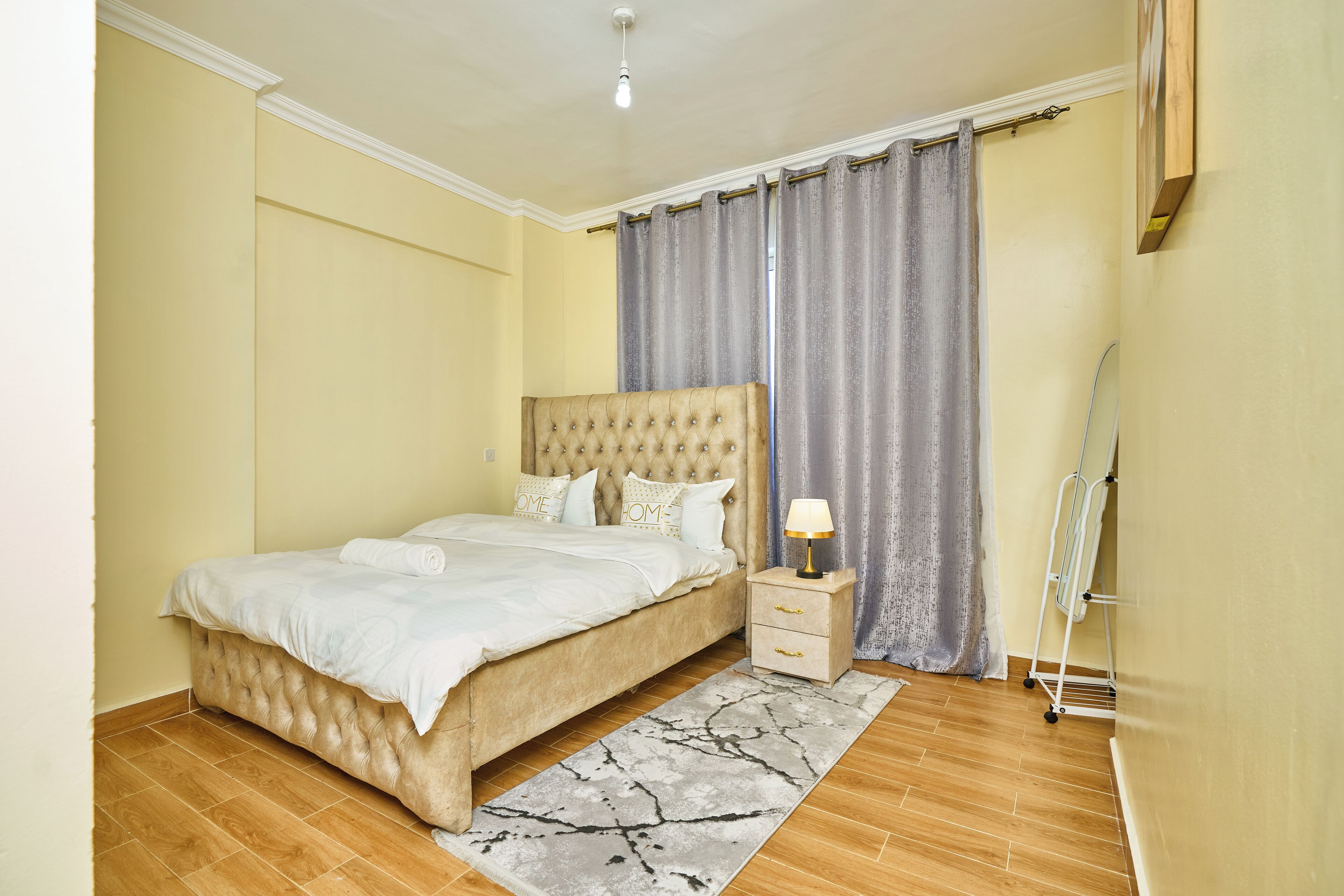 A bedroom with a large bed, bedside tables, a lamp, and a window with curtains.