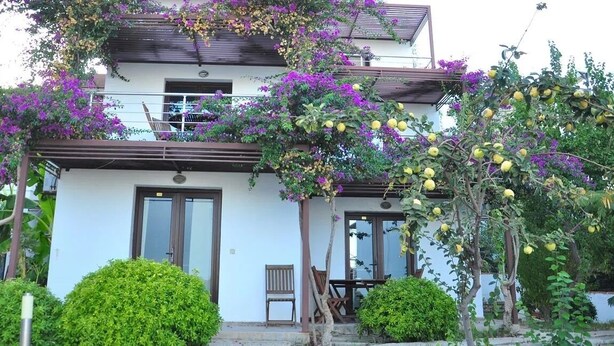 A two-story building with a balcony, a door, and a small porch with a chair. - Milport Hotel Bodrum (Bitez)