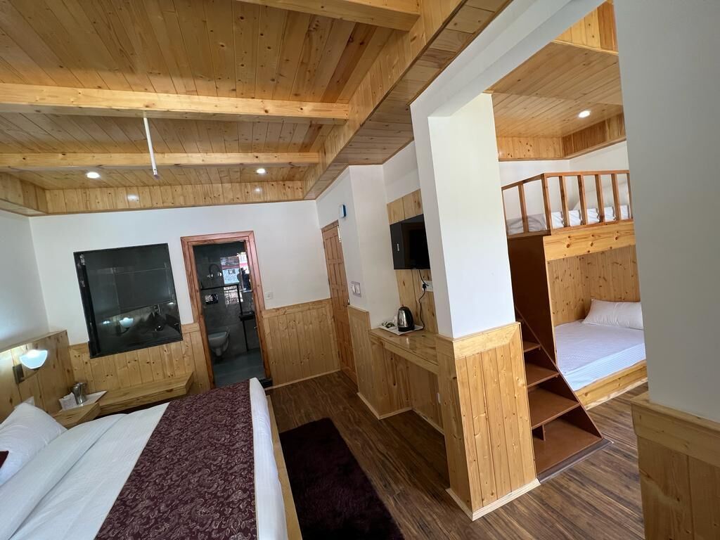 Una habitación tipo cabaña de madera con una litera, un escritorio y un televisor.