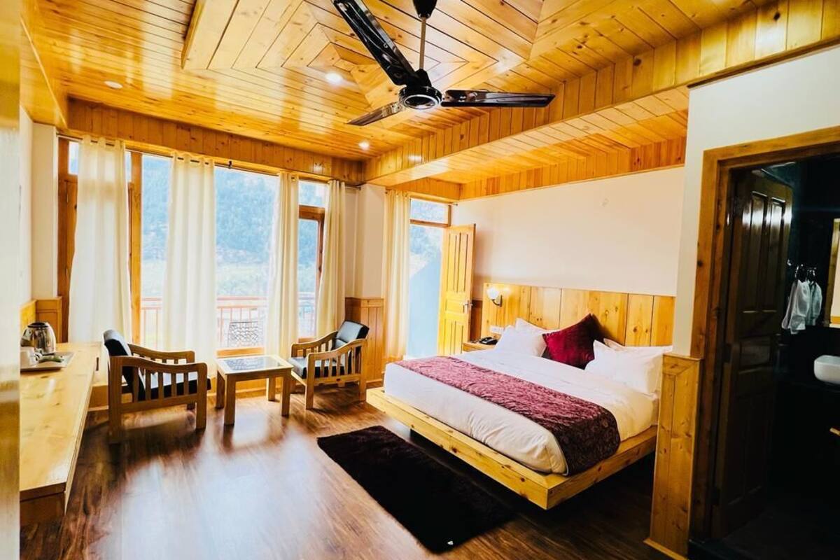 A wooden-floored bedroom with a bed, a desk, and chairs.