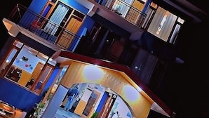 A multi-story building with balconies, a staircase, and a well-lit entrance. - Hotel Sakura Palace (Manali)