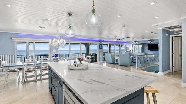Una cocina amplia con una isla grande, iluminación colgante moderna y vistas al océano.