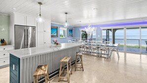 Una cocina moderna con una isla grande, electrodomésticos de acero inoxidable y vistas al océano.