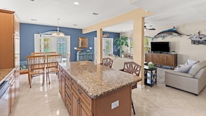 A spacious kitchen with granite countertops, wooden cabinets, and a dining area with chairs.