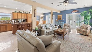 A spacious living area with a sofa, coffee table, and a dining area with wooden cabinets and chairs.
