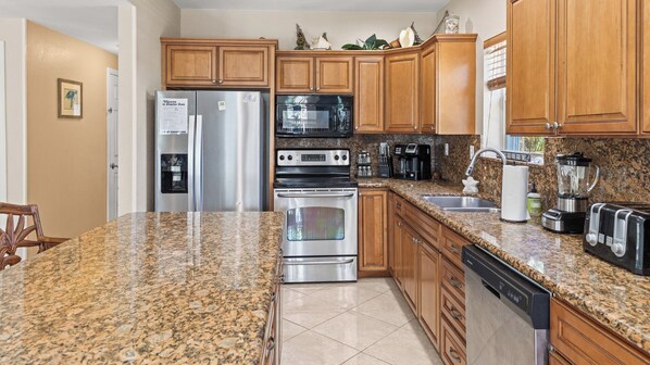 A kitchen with granite countertops, stainless steel appliances, wooden cabinets, and a dishwasher.