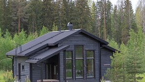 A modern cabin with a sloped roof, large windows, and a porch area.