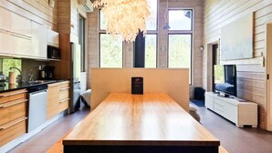 A modern kitchen with wooden cabinets, a dining table, and a hanging light fixture.