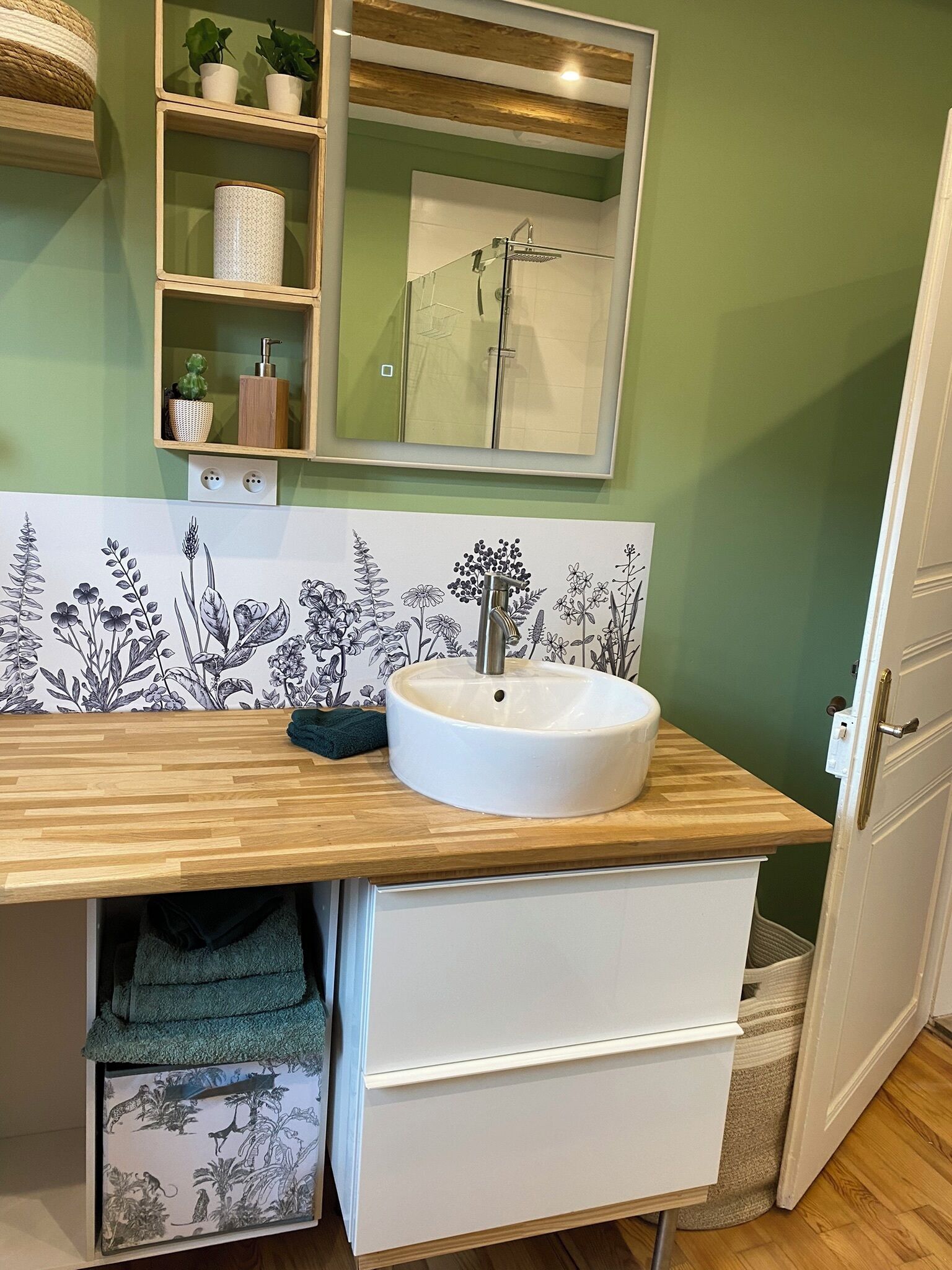 Un baño con tocador de madera, lavamanos blanco, espejo y ducha.
