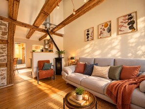 A cozy living room with a sofa, a chair, a coffee table with a plant, and artwork on the wall.