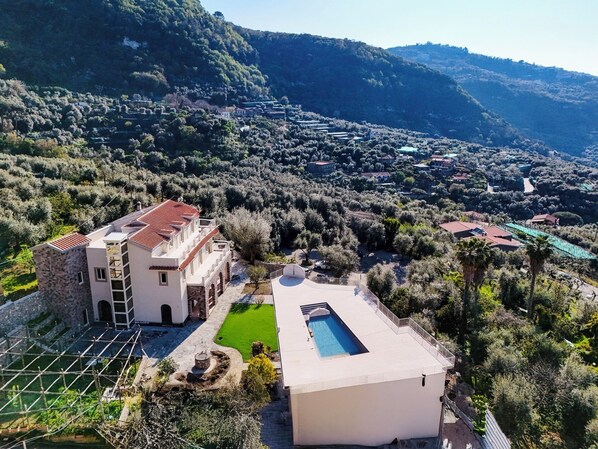 A villa with a swimming pool, terraced garden, and a view of the surrounding hills. - Villa Gialisa (Sorrento)