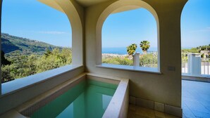 Une piscine avec vue sur la mer et les collines.