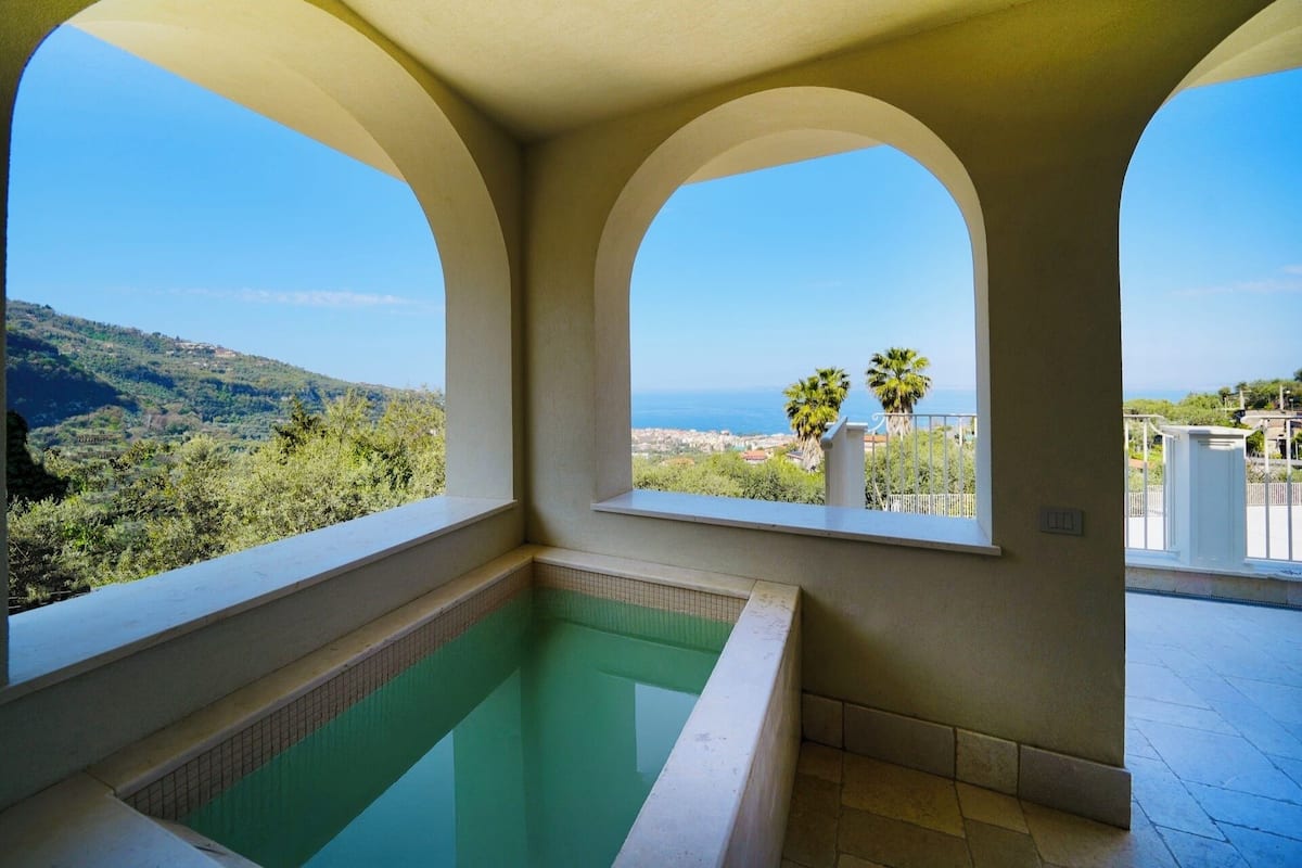 A swimming pool with a view of the sea and hills.