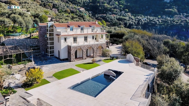 Une vaste villa dotée d’une piscine, entourée d’une végétation luxuriante et de collines.