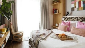 A hotel room with a bed, a desk, a chair, a bookshelf, and a large window with curtains.