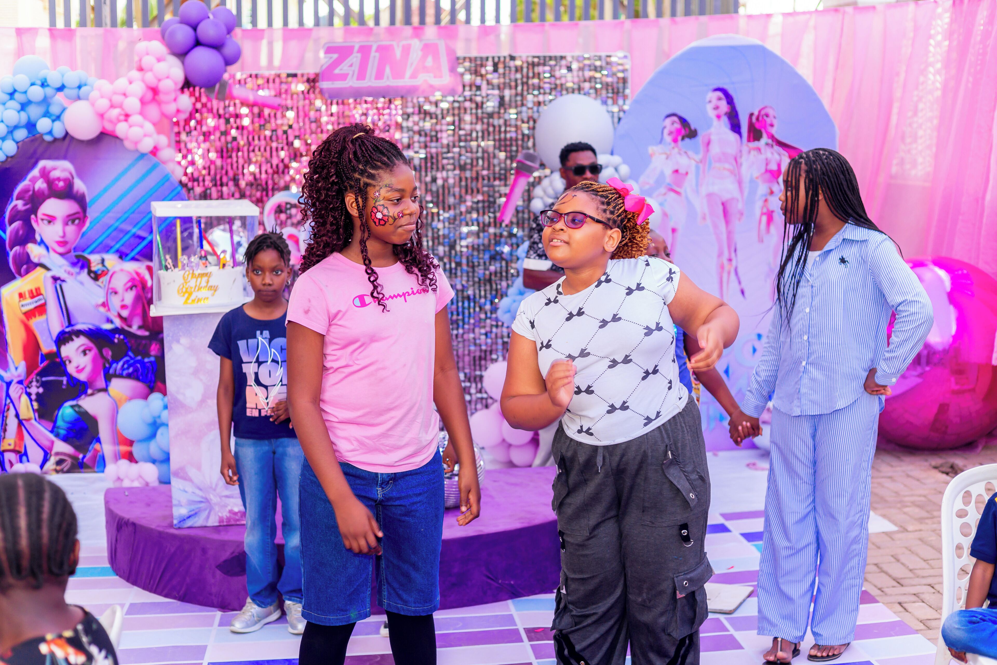 A stage with a pink and purple color scheme, featuring balloons and a backdrop with cartoon characters.