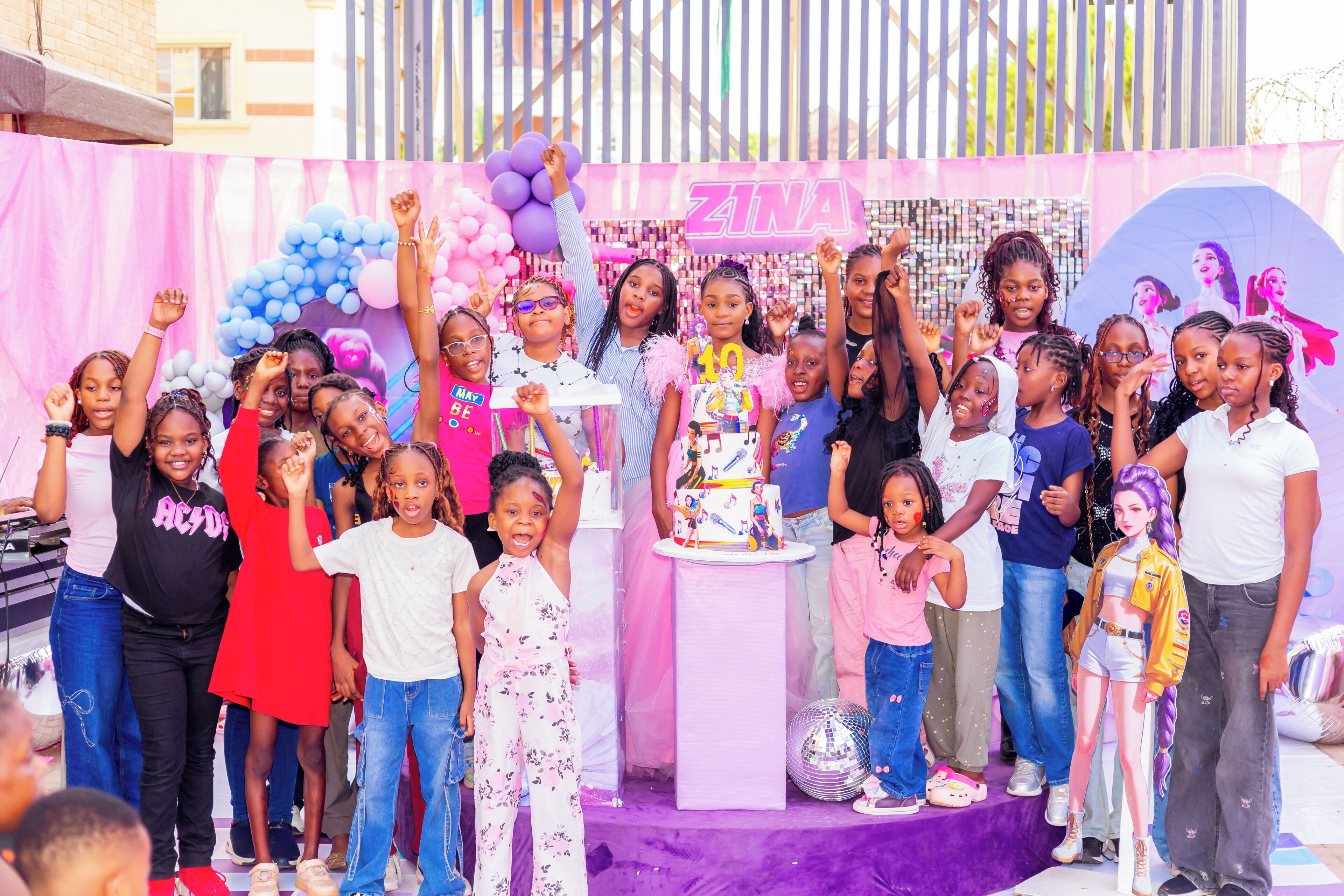 A group of people at a celebration with a cake and balloons.