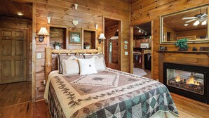 Une chambre confortable dans un chalet en rondins, avec un grand lit, une cheminée et des murs en bois.