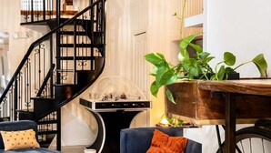 A modern living room with a staircase, blue sofas, a table, and a bicycle wheel. - Charming Retreat in Eastman | Spa, Bike & Hike ! (Eastman)