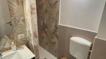 A bathroom with a shower, toilet, and sink.