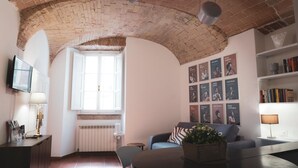A cozy living room with a brick ceiling, a window, a sofa, a coffee table, and a bookshelf.