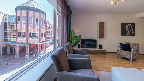Uma sala de estar moderna com uma janela grande, uma televisão de tela plana, um sofá e uma mesa de centro.