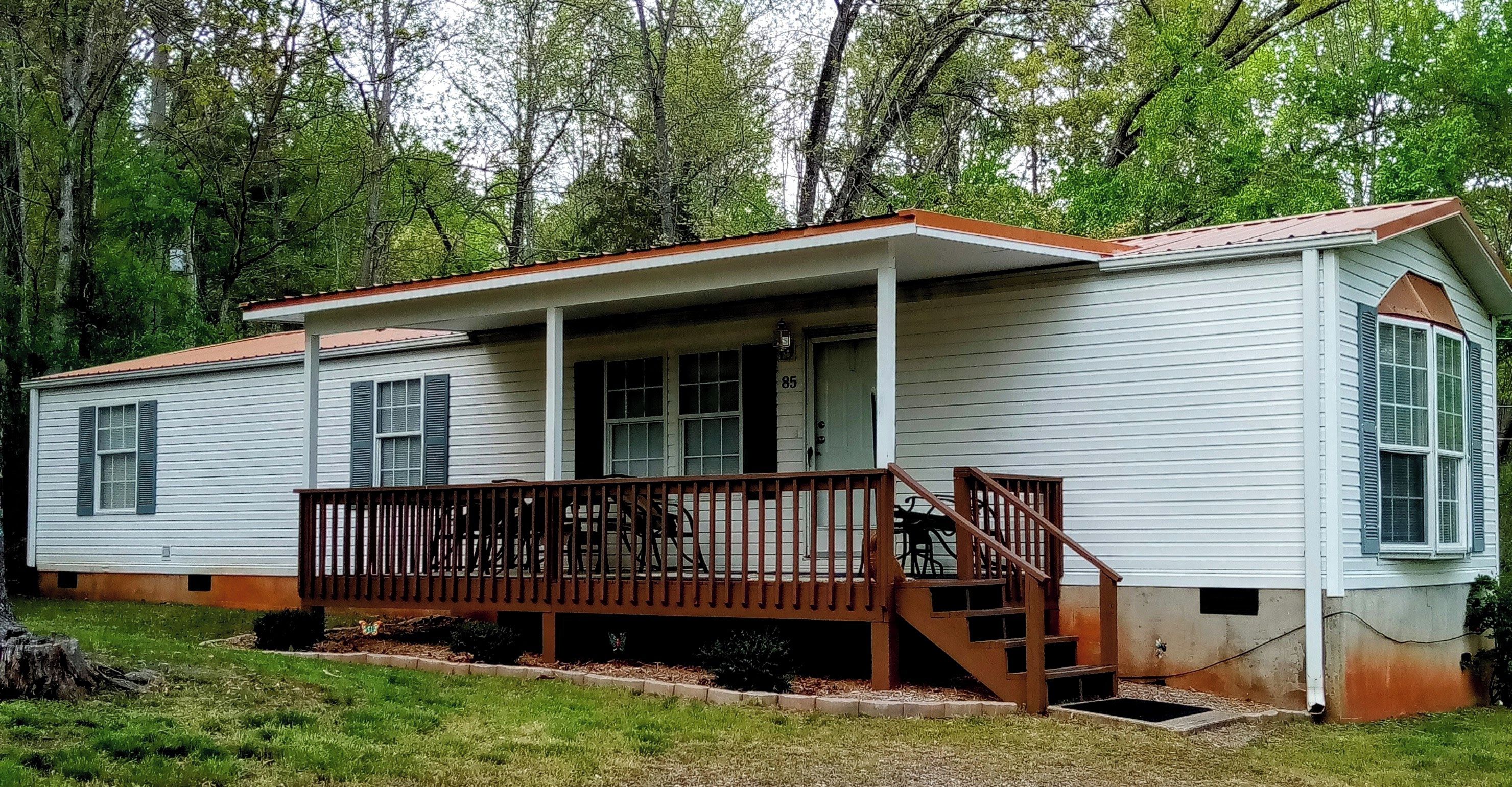 A single-story mobile home with a porch and a small staircase leading to the entrance.