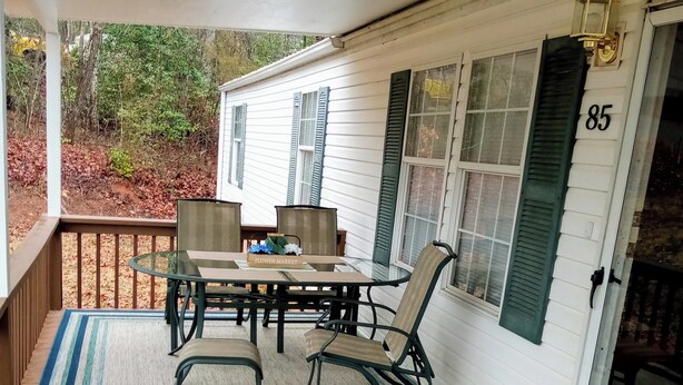 A covered porch with a table and chairs, a rug, and a door marked with the number 85. - "Holland Hills" offers a clean, quiet, comfortable stay. Paved access. Nice area (Franklin)