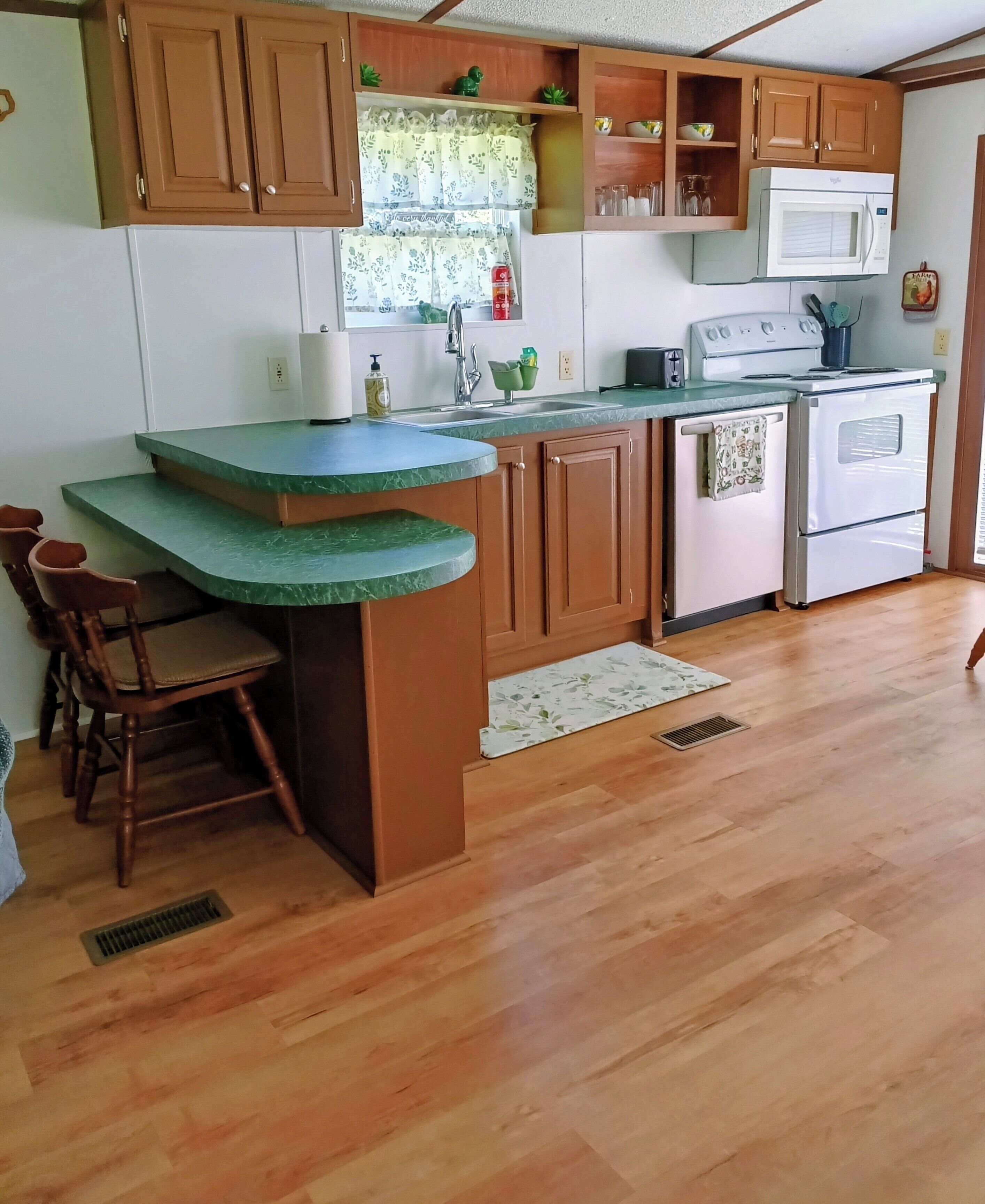 A kitchen with wooden cabinets, a green countertop, a sink, a microwave, and an oven.