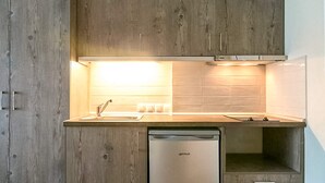Eine moderne Küche mit Holzausstattung, einem Edelstahl-Geschirrspüler und einer hellen Beleuchtung unter den Schränken.