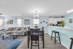 Una sala de estar moderna con comedor, cocina y una pared de acento azul claro.