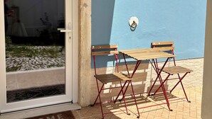 Eine Terrasse mit Tisch und Stühlen, einer Tür und einer kleinen Wandleuchte.