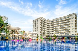 Un hotel con una gran piscina, asientos al aire libre y un tobogán de agua.