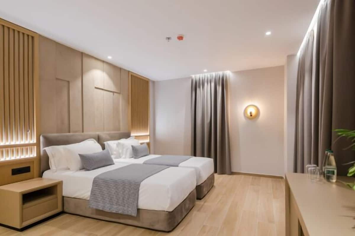 Une chambre d’hôtel moderne, dotée d’un grand lit, de tables de chevet, d’un bureau et d’un luminaire fixé au mur.